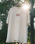 Beige oversized t-shirt with 'Gravy Baby' text on a hanger against a natural background.